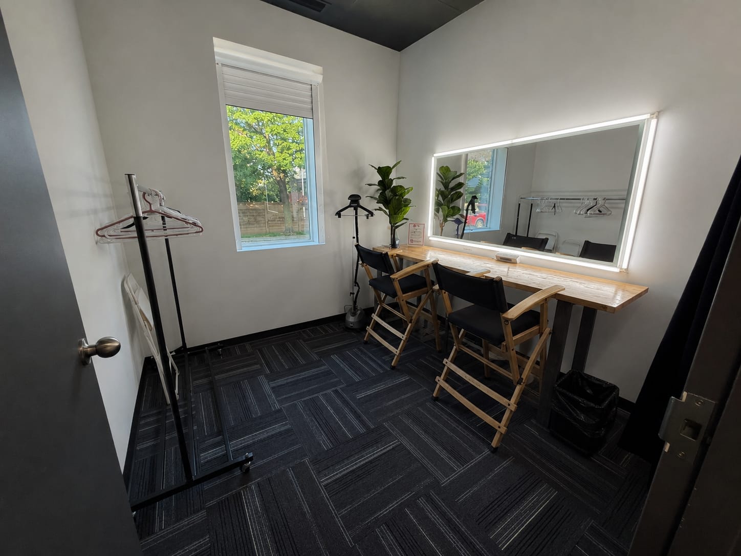 Hair and makeup room with a lit mirror and wardrobe rack at Viva Studios